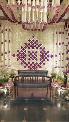 a bench sitting under a chandelier in front of a wall covered with flowers