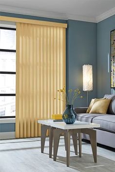 a living room with blue walls and yellow vertical blinds on the window sill in front of the couch