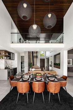 a dining room table and chairs in front of an open floor plan with high ceilings