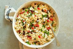 a white bowl filled with pasta salad on top of a wooden table next to a napkin