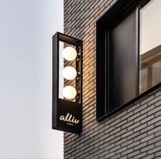 a sign on the side of a brick building that says allu with three lights