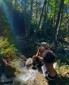 a woman sitting on top of a rock next to a river