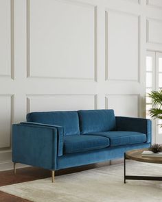 a living room with a blue couch and coffee table in front of a white wall