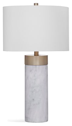 a white marble lamp with a gold base and a white drum light shade on top