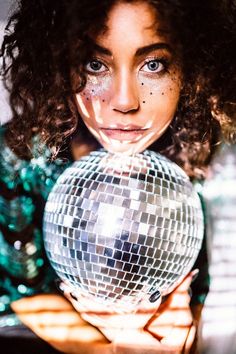 a woman holding a disco ball in front of her face