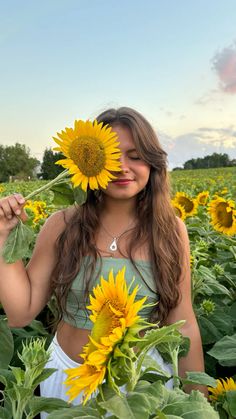 a woman standing in the middle of a field with sunflowers