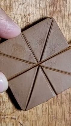 a person holding a piece of chocolate in their hand on top of a wooden table