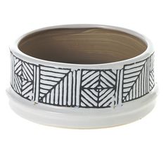 a white and black bowl with designs on the bottom, sitting in front of a white background