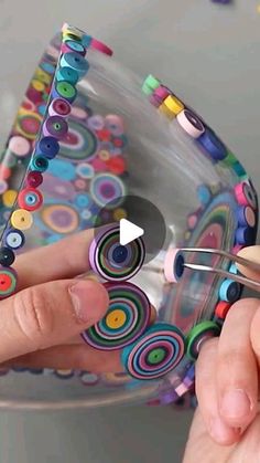 a person is holding scissors in front of a glass bowl with buttons on the inside