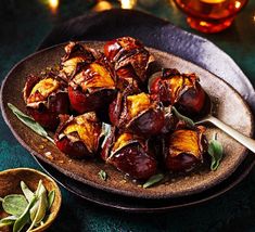 roasted eggplant with sage leaves on a platter next to a cup of tea