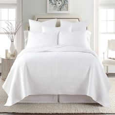 a bed with white sheets and pillows in a room