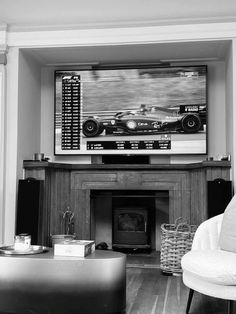 a black and white photo of a living room with a television on the wall above a fire place