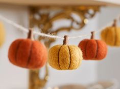 small felt pumpkins hanging from a string in front of a gold chandelier