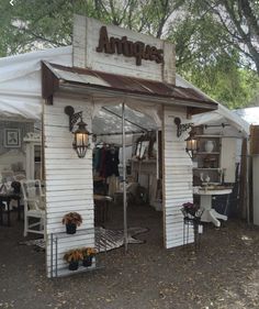 an antique store with white walls and wooden doors, in the middle of a dirt lot