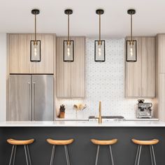 three stools sit in front of a kitchen island with four pendant lights hanging over it