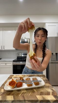 a woman is holding up a hot dog on a plate with ketchup and mustard