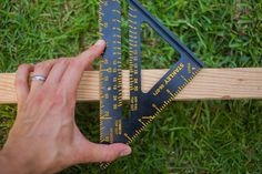 a person is measuring the length of a wooden plank with a pair of black rulers