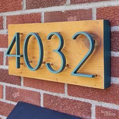 a wooden house number sign mounted to a brick wall