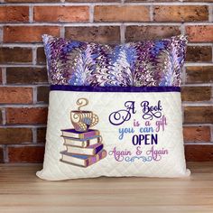 a pillow that has some books and a cup on it with the words, a book is