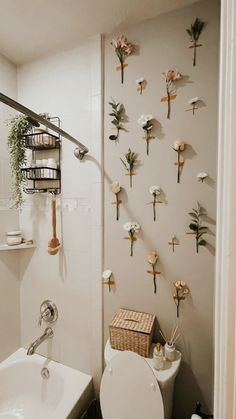 a white toilet sitting next to a bath tub in a bathroom with flowers on the wall