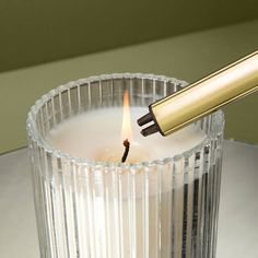 a candle with a lighter sticking out of it's top in a glass container