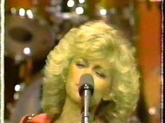 a woman with blonde hair singing into a microphone