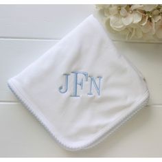 a white towel with the letter jfn on it next to a bouquet of flowers