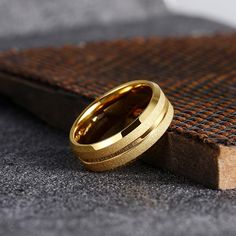 two gold wedding bands sitting on top of a piece of wood