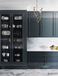 an elegant kitchen with marble counter tops and dark blue cabinets, along with white dishes