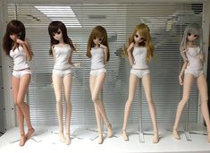 five dolls are posed in front of a window