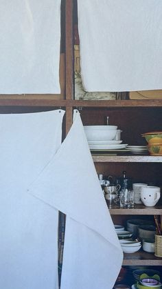 two white towels are hanging on the wall in front of a shelf full of dishes