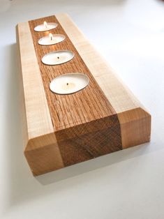 three candles are placed on top of a piece of wood that has been turned into a candle holder