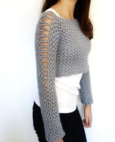 a woman is wearing a gray sweater with crochet on the sleeves and shoulders