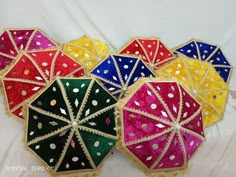 four colorful umbrellas are sitting on a white sheet with polka dots and sequins