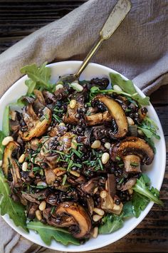 a white bowl filled with mushrooms and greens