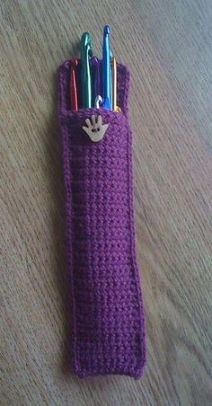 a purple crocheted pencil holder with pens in it