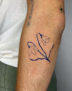 a man with a tattoo on his arm that has a blue outline of a flower