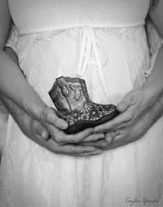 a pregnant woman holding her baby boot in her hands, black and white photograph with lace dress