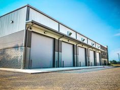 an industrial building with several roller up doors on the front and side of it, against a blue sky