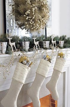 christmas stockings hanging from the mantel in front of a fireplace with silver and gold decorations