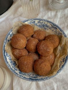 a blue and white bowl filled with sugared donuts on top of a table