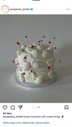 a white wedding cake with red berries on top and the word love spelled in small letters