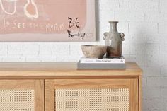 a table with two vases on top of it next to a painting and books