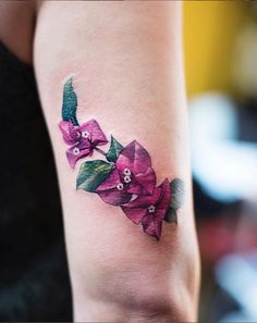 a woman with a tattoo on her arm has pink flowers and leaves painted on it