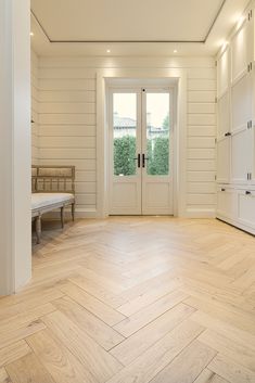 an empty room with white walls and wooden floors, two benches on either side of the door