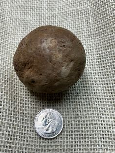 a penny sitting next to a rock on top of a cloth