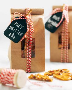 two brown paper bags with red and white striped twine on them, one has a tag that says nut brittle