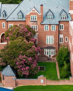 an aerial view of a large brick building with green grass and trees in the foreground