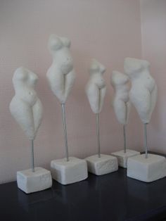 five white sculptures are lined up on a black table