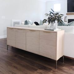 a white couch sitting next to a wooden cabinet on top of a hard wood floor